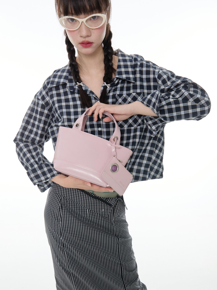 Pink handbag held by a model wearing a plaid shirt