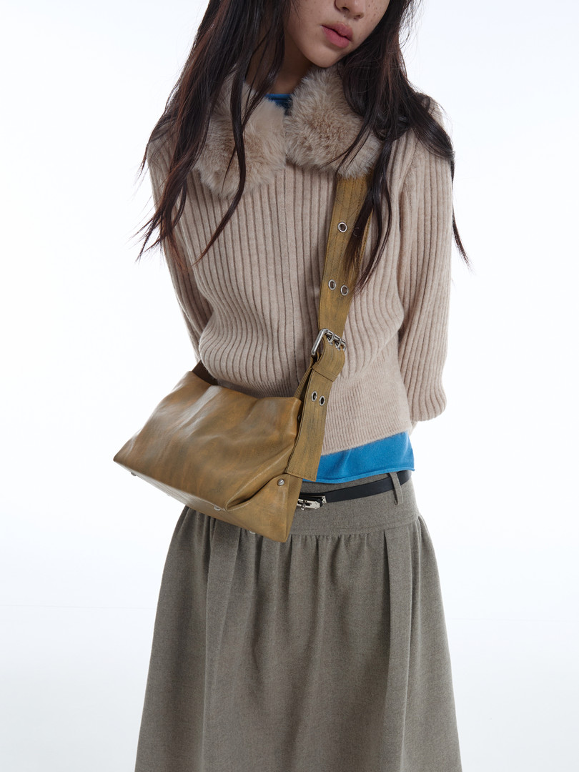 Model wearing a beige ribbed sweater with fur collar and a tan crossbody bag