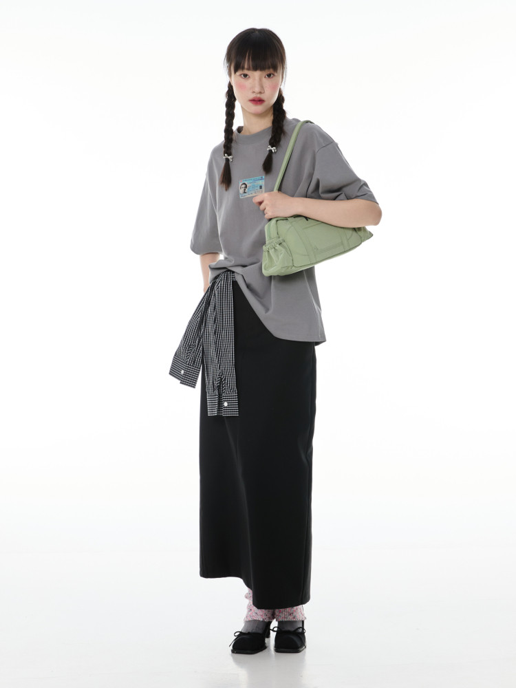 Fashion model wearing a gray oversized top, black skirt, and light green shoulder bag
