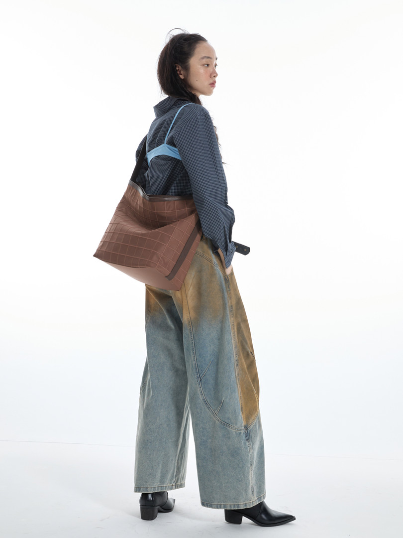 Model wearing oversized jeans and carrying a brown crossbody bag