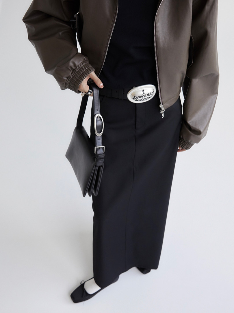 Model wearing a brown jacket with a black skirt and black handbag
