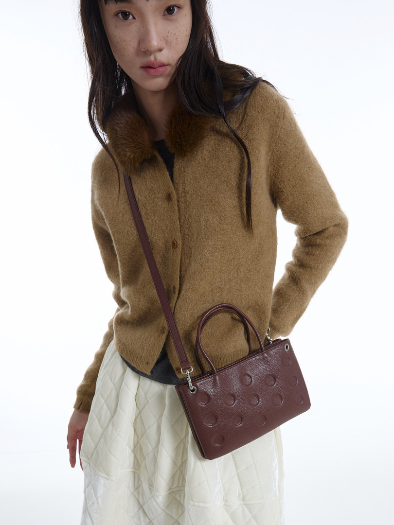 Model wearing a brown fuzzy cardigan with a burgundy shoulder bag