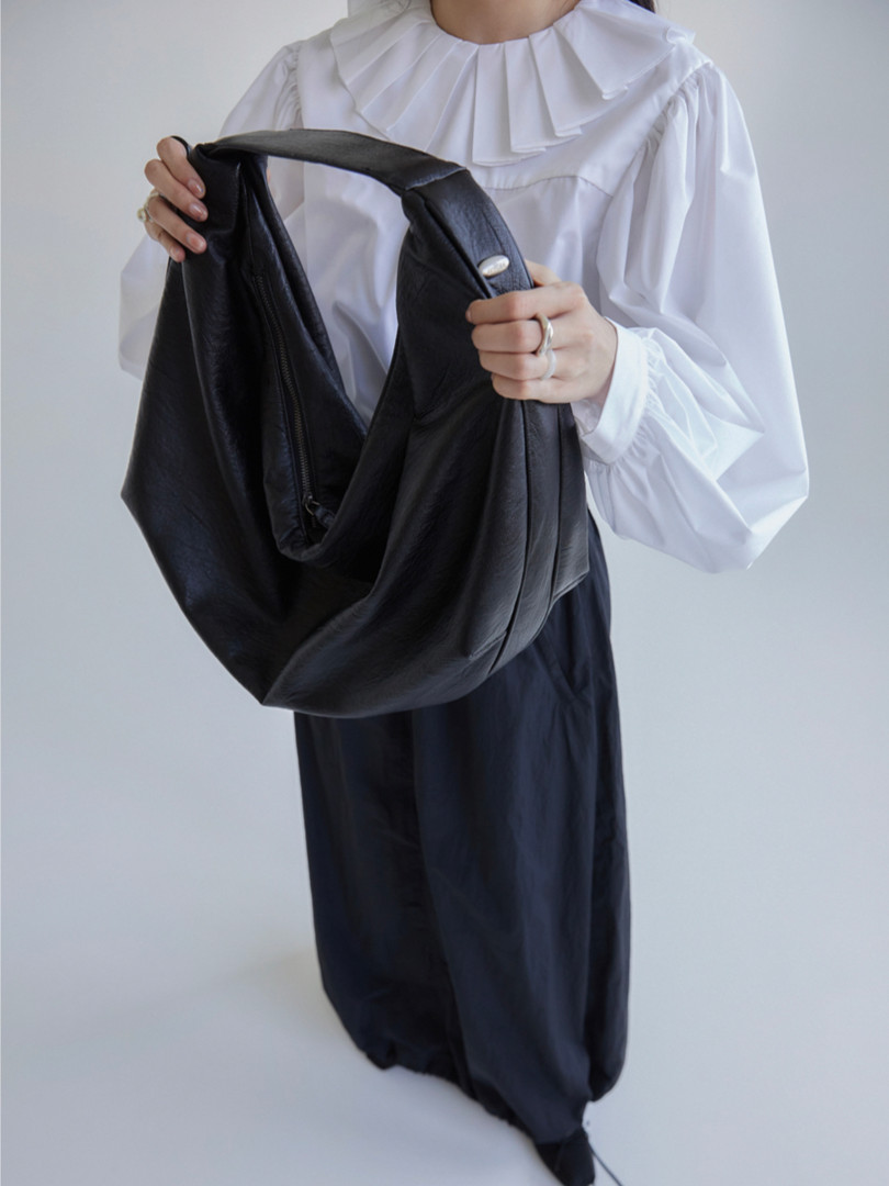 Black leather slouchy handbag held by a model