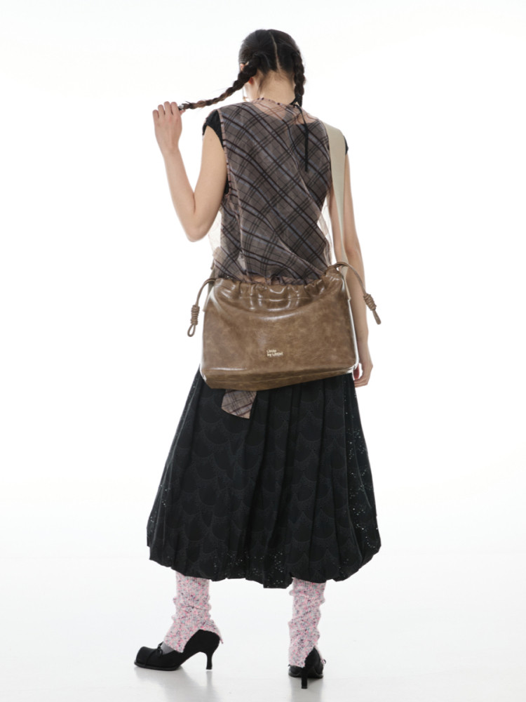 Brown leather shoulder bag worn by a model with a patterned outfit