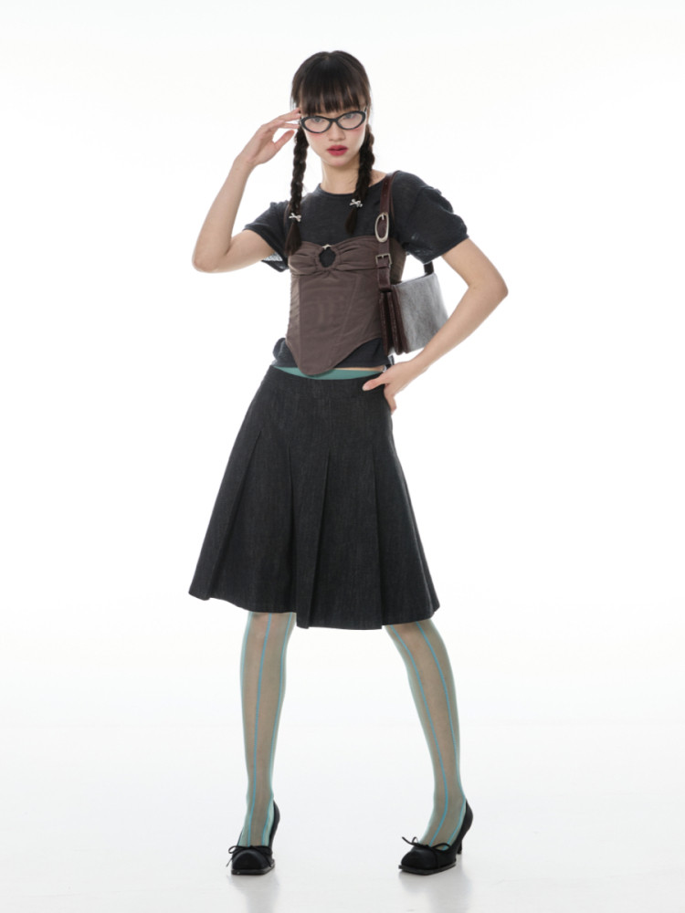 Fashion model wearing a dark top, skirt, and handbag on a white background