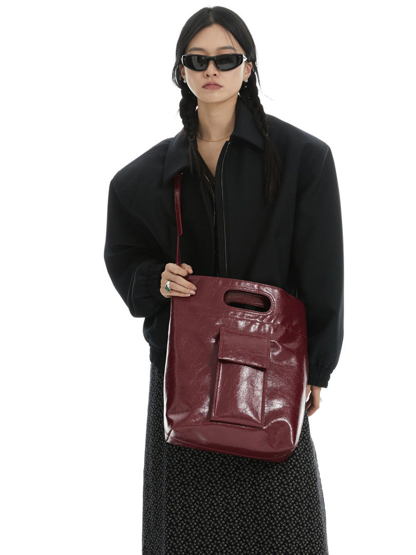 Burgundy glossy leather shoulder bag worn by a model