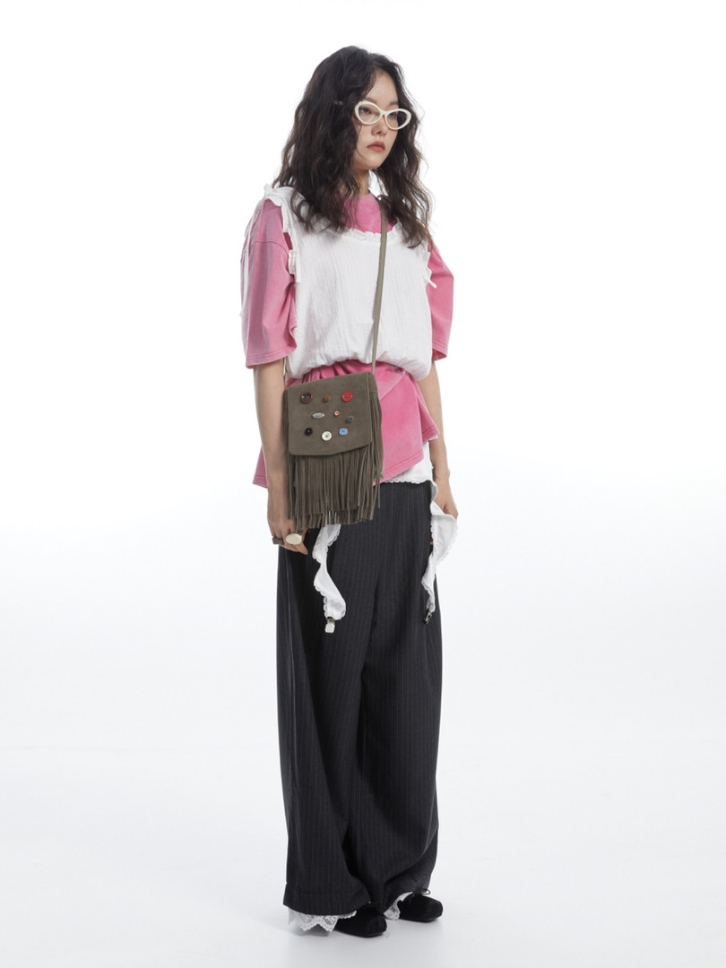 Full-length model wearing a pink layered outfit with a crossbody bag on a white background