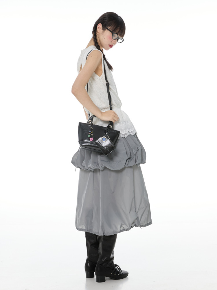Fashion model wearing a layered gray skirt outfit with a black shoulder bag