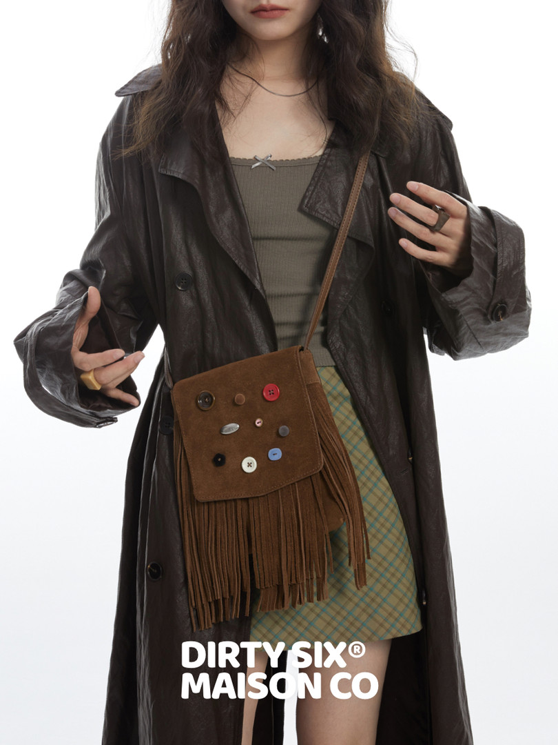 Fashion model wearing a brown fringe crossbody bag with a dark leather trench coat