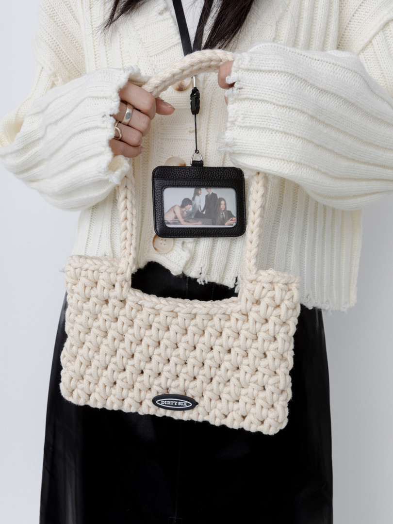 Cream crocheted tote bag held in front of a white sweater outfit