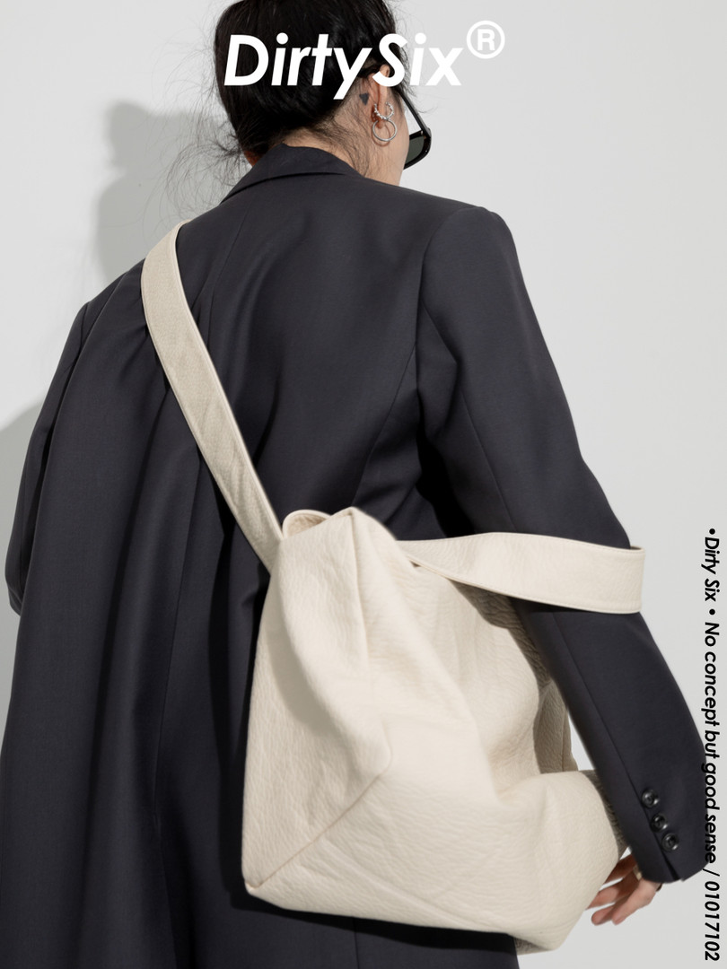 Beige shoulder tote bag worn by a model over a dark blazer