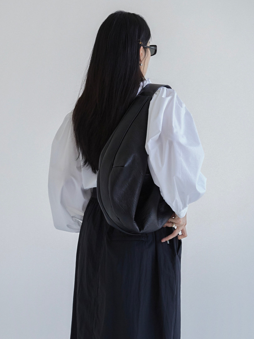 Black leather shoulder bag worn on a model's back
