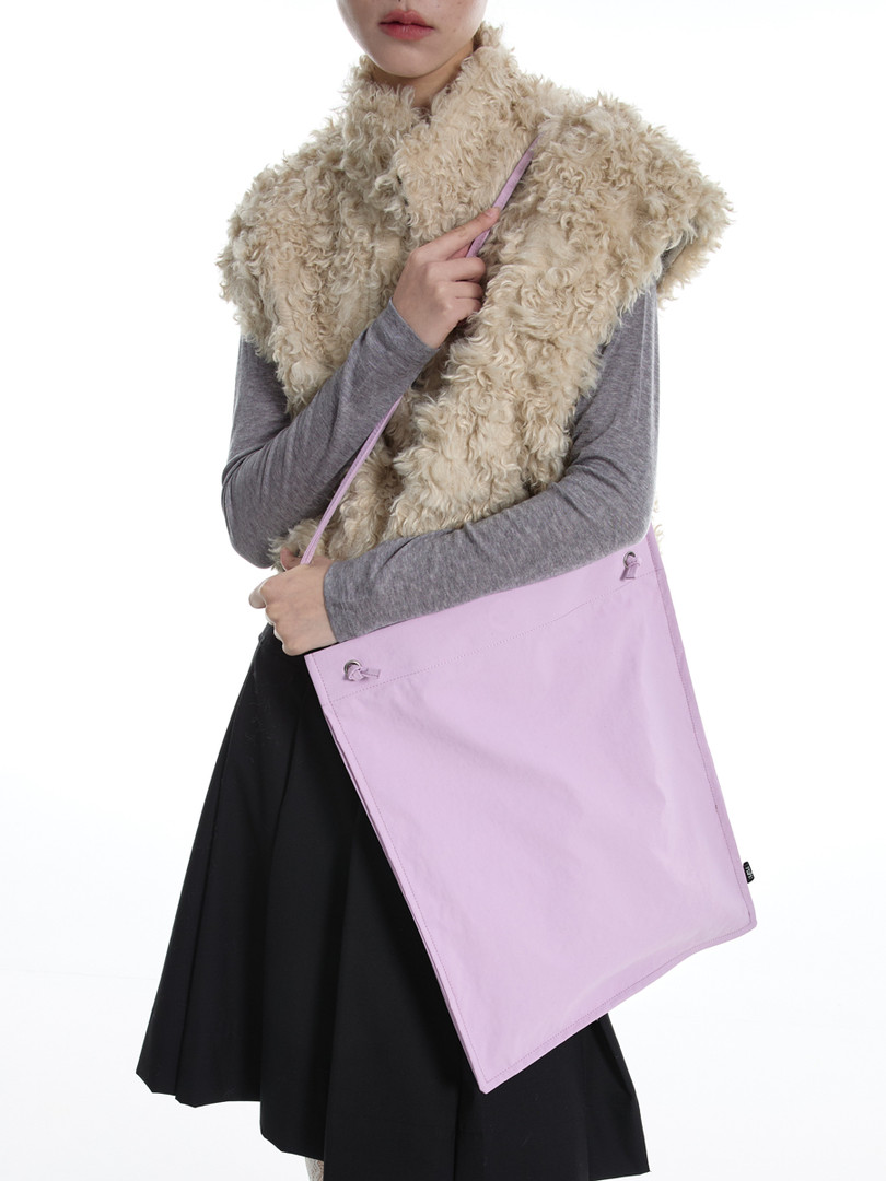 Model wearing a fluffy beige faux fur vest and a lavender crossbody bag