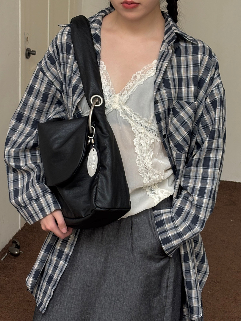 Plaid oversized shirt layered over a lace camisole with a black shoulder bag on a model