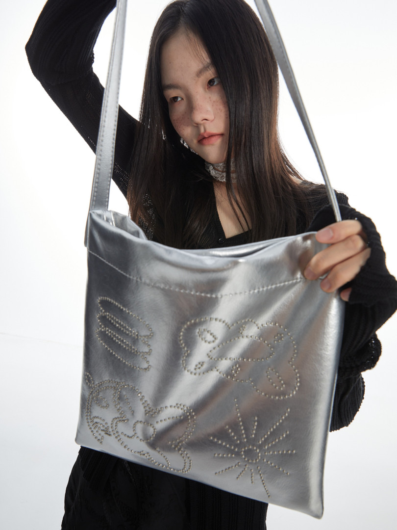 Silver metallic shoulder bag held by a model