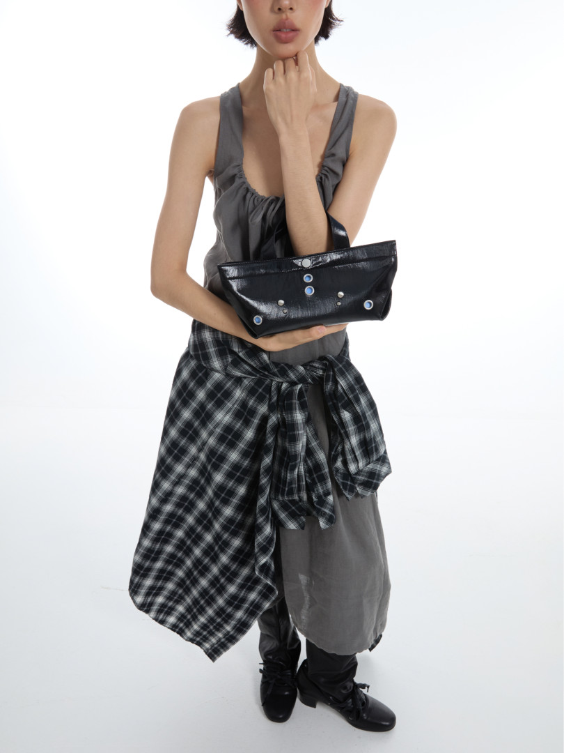 Fashion model wearing a gray outfit and holding a black studded handbag