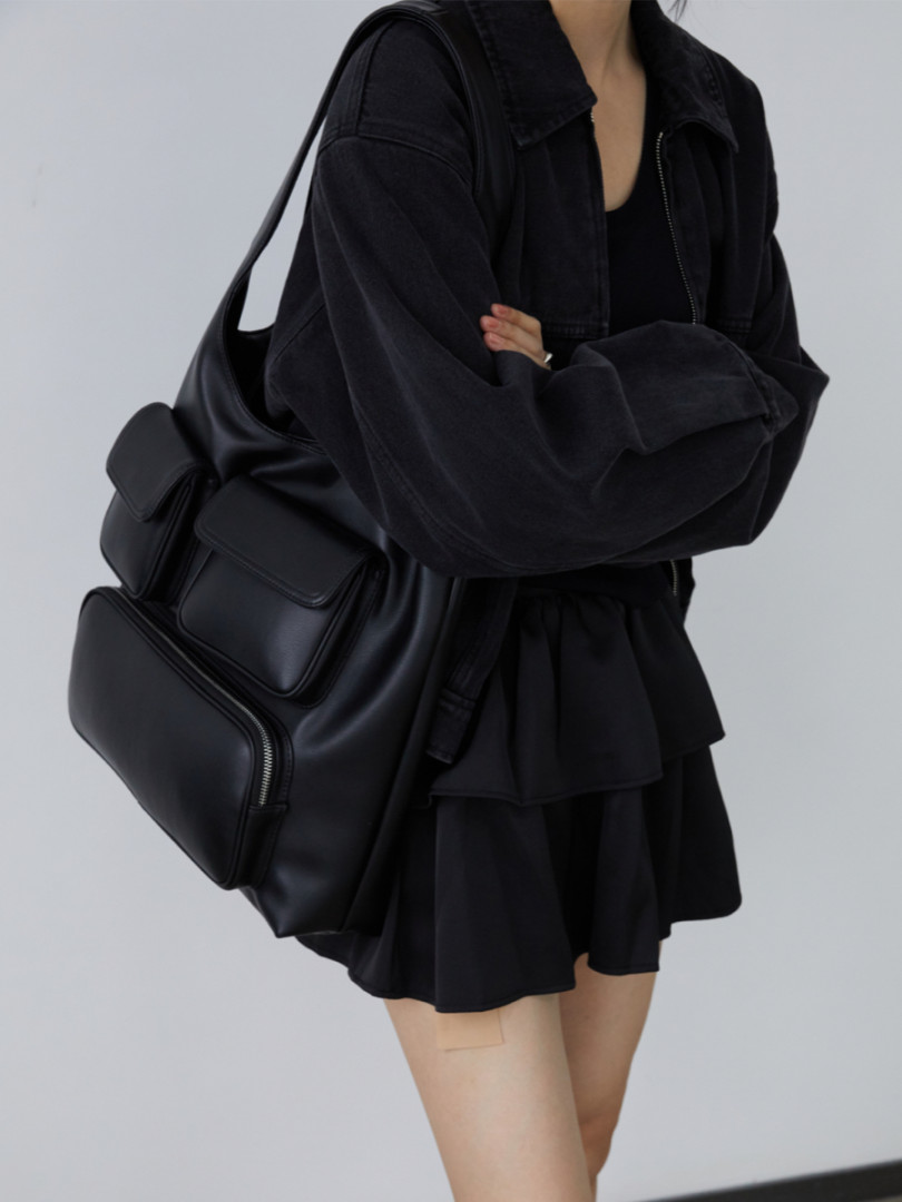 Model wearing an oversized black outfit with a large black shoulder bag