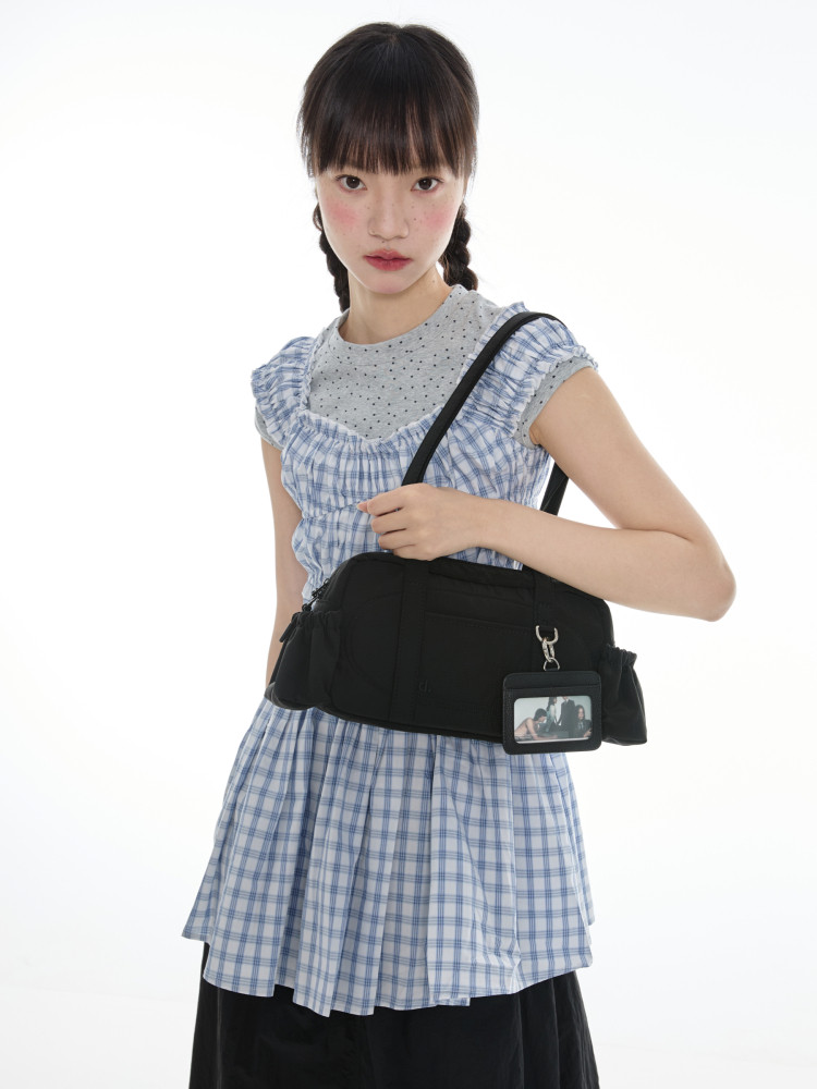 Model wearing a blue plaid dress with a black waist bag