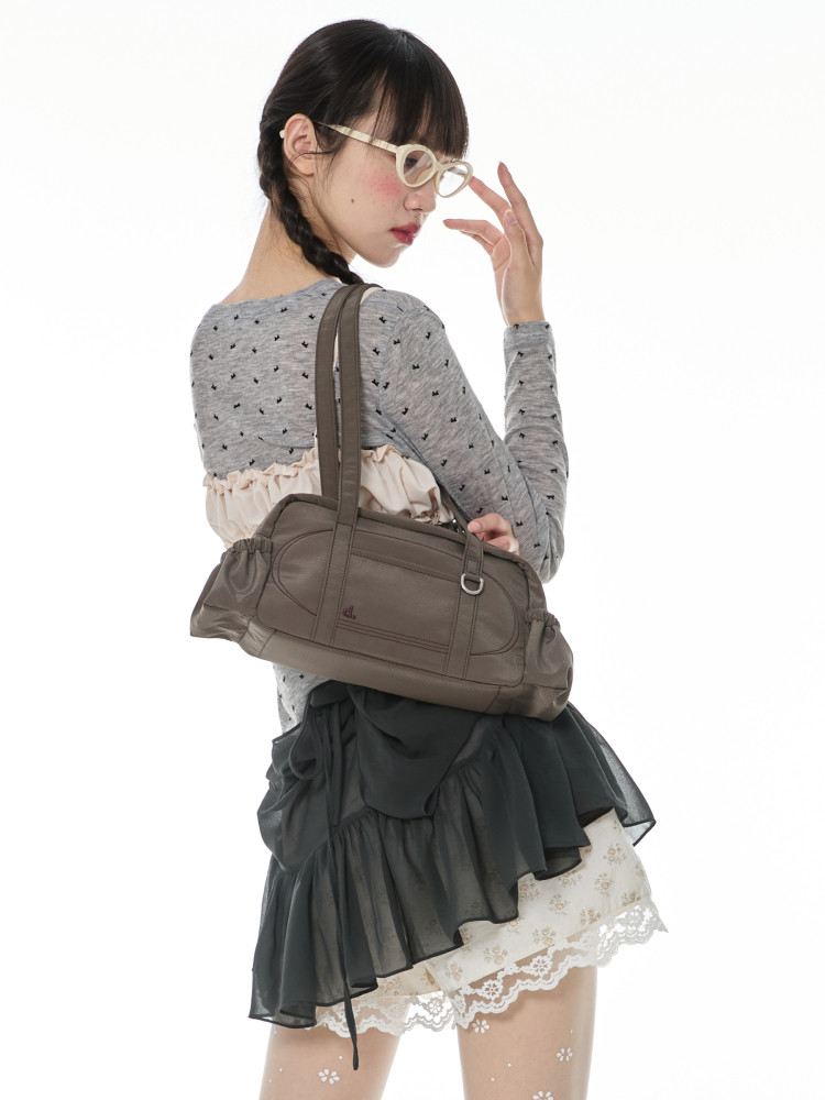 Model wearing a gray dress and carrying a brown handbag