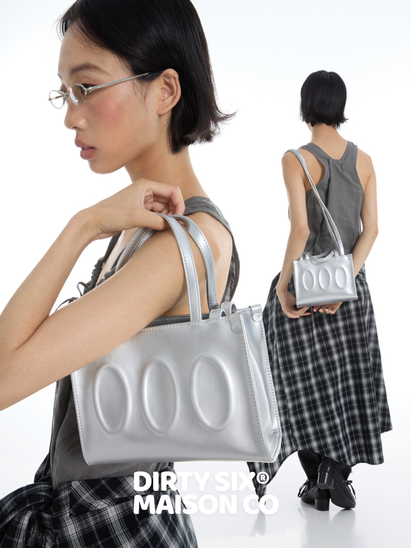 Silver handbag carried by a model with a matching fashion outfit