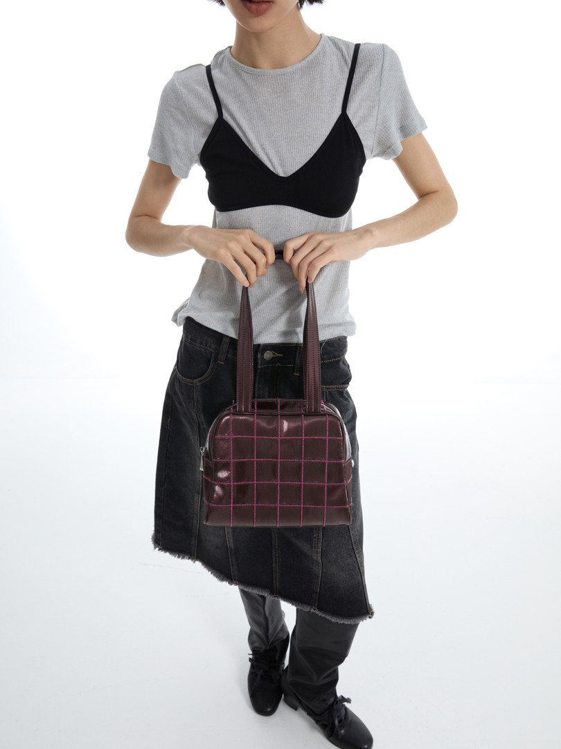 Model wearing a black and burgundy checkered shoulder bag with a casual outfit