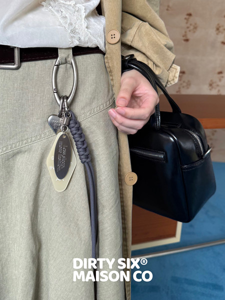 Model wearing a beige outfit with a black leather backpack and hanging keychain accessories