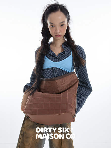 Model wearing a brown quilted shoulder bag with a plaid shirt outfit