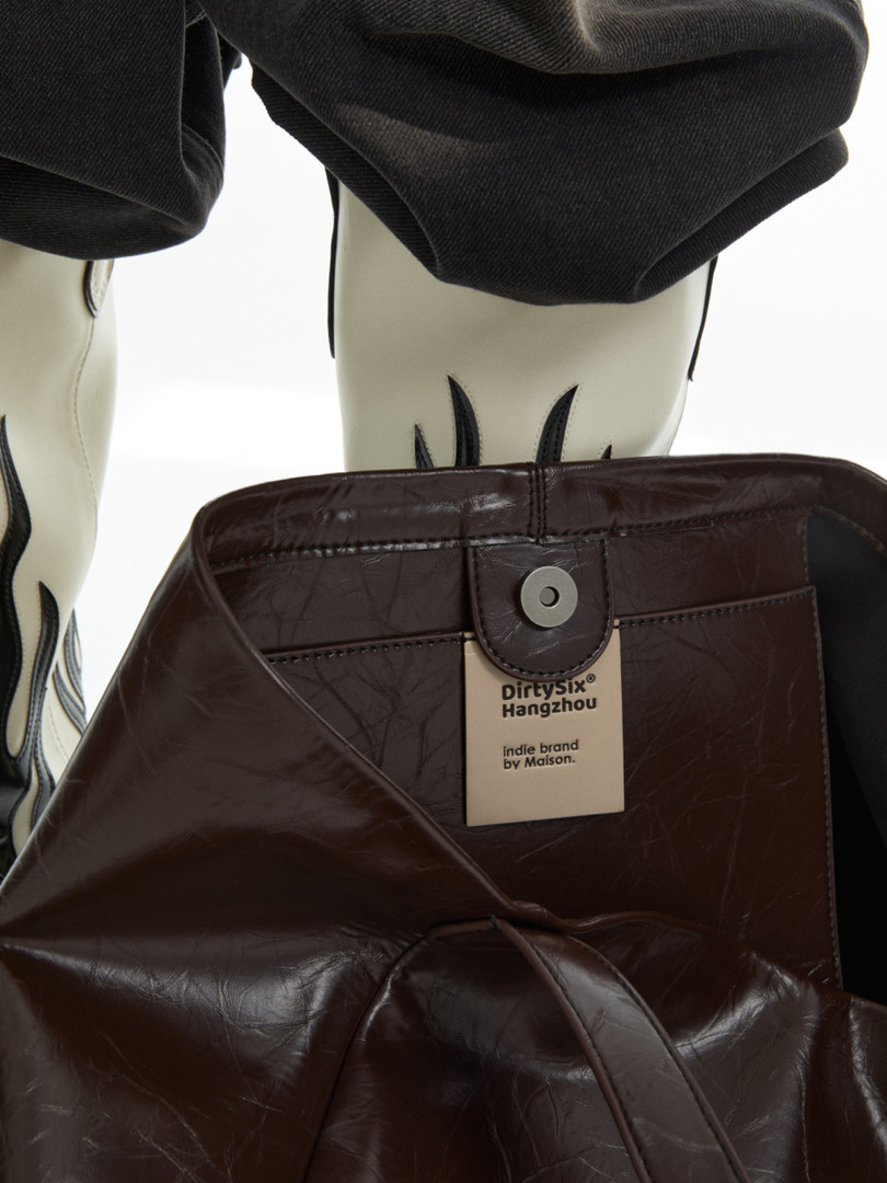 Brown leather handbag with brand tag shown in a product display
