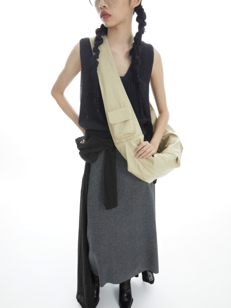Model wearing a black knit outfit with a beige crossbody bag