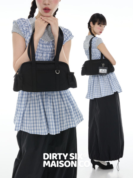 Black shoulder bag worn by a model with a blue plaid outfit