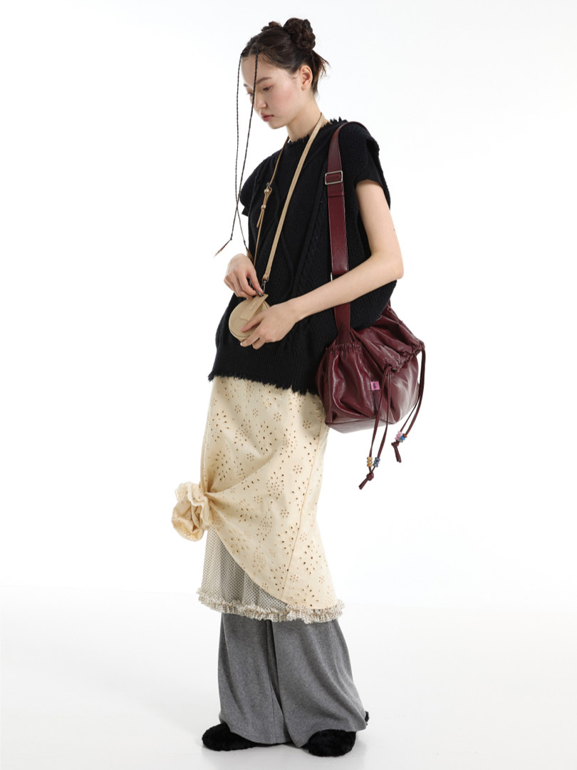 Model wearing a layered boho-style outfit with a burgundy shoulder bag on a white background