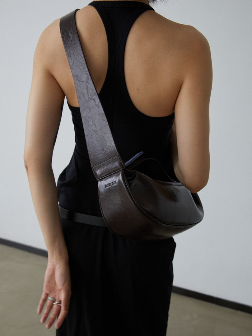 Black leather shoulder bag worn crossbody on a model
