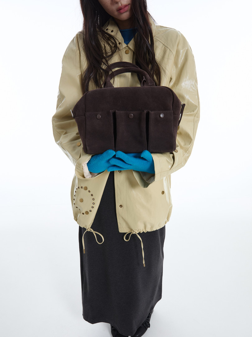 Brown structured handbag held by a model in a studio shot