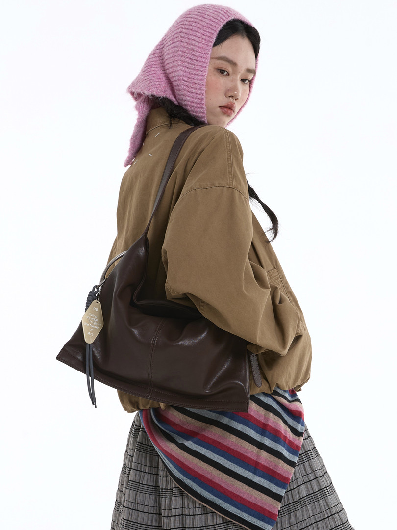 Model wearing a dark brown leather shoulder bag with layered casual outfit