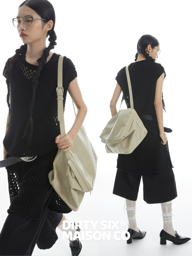 Model wearing a black mesh layered outfit with a beige shoulder bag