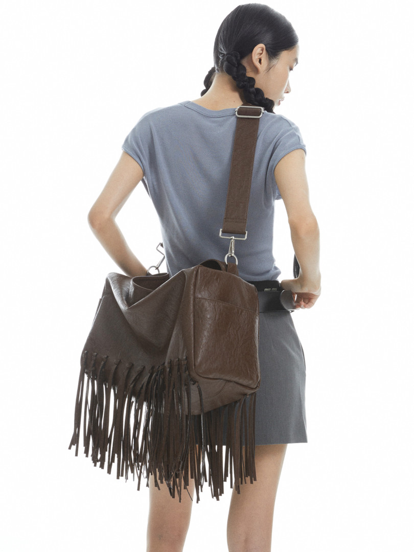 Brown fringed leather shoulder bag worn on a model