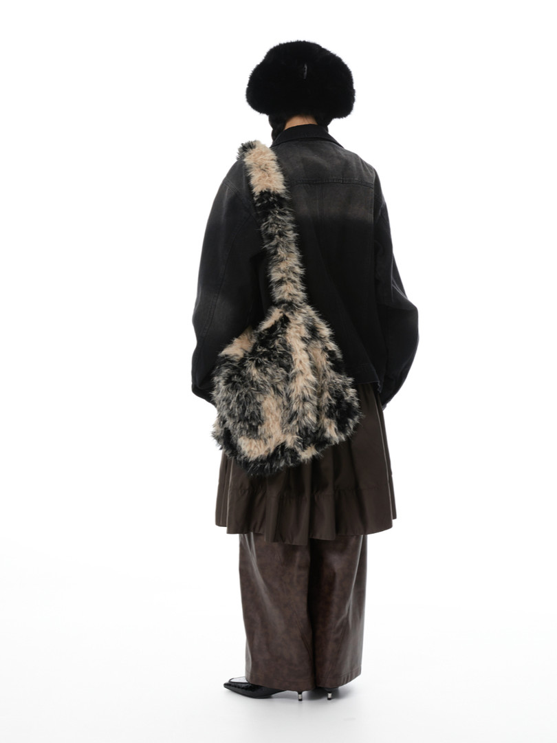 Model wearing a black jacket with a large faux-fur crossbody bag and fur hat