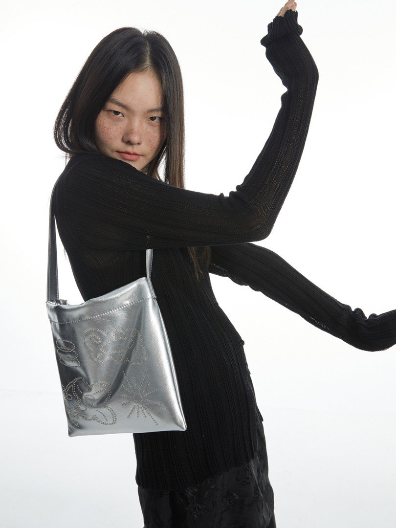 Model wearing a black ribbed knit long-sleeve outfit with a silver shoulder bag
