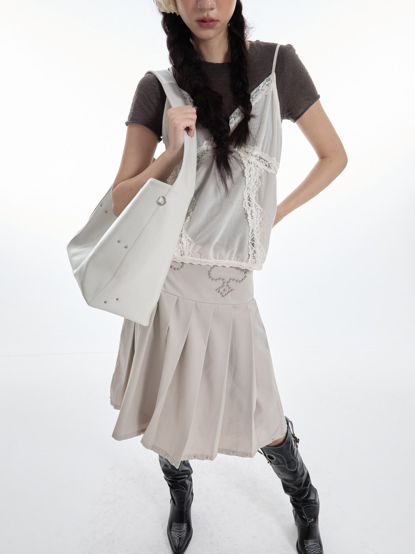 Fashion model wearing a layered light beige outfit with a white tote bag and black boots