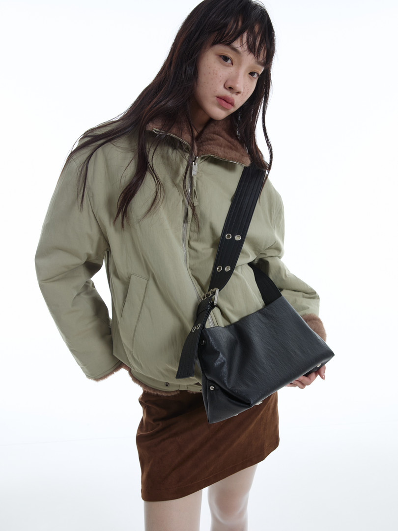 Model wearing a light olive jacket with a black crossbody bag