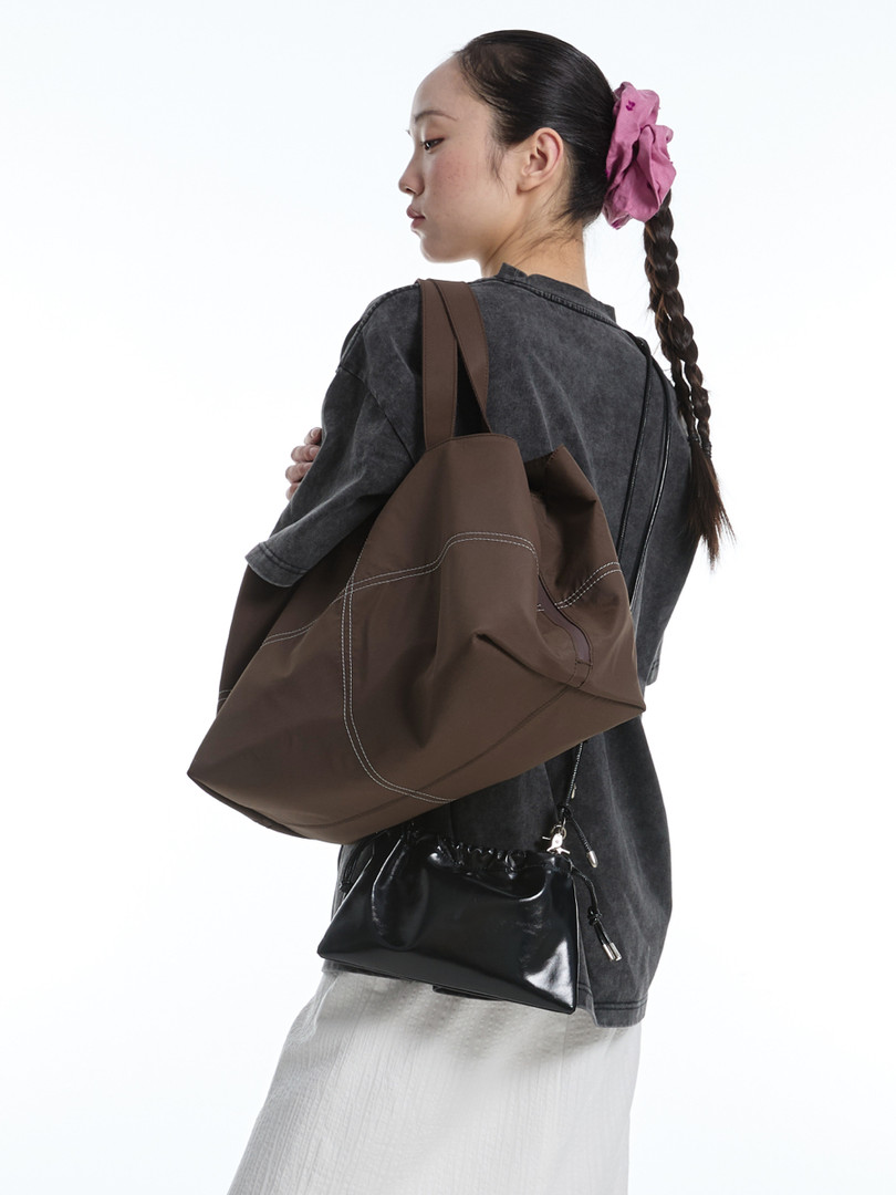 Woman wearing a large brown tote bag with a small black shoulder bag