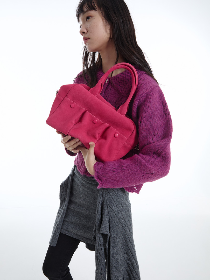 Pink handbag held by a model wearing a purple sweater
