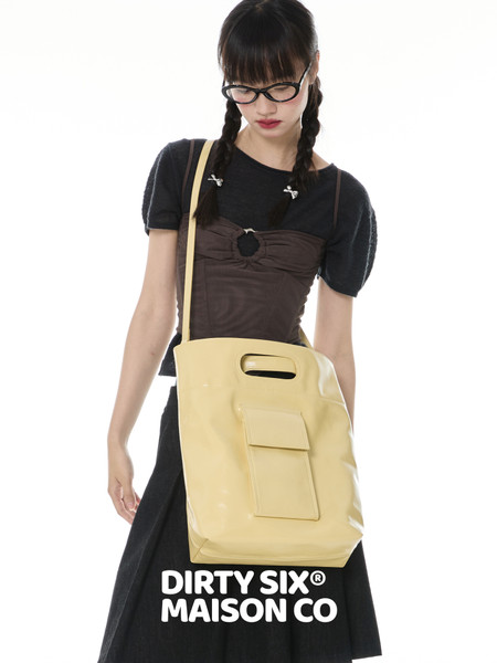 Model wearing a black outfit with a large pale yellow shoulder bag