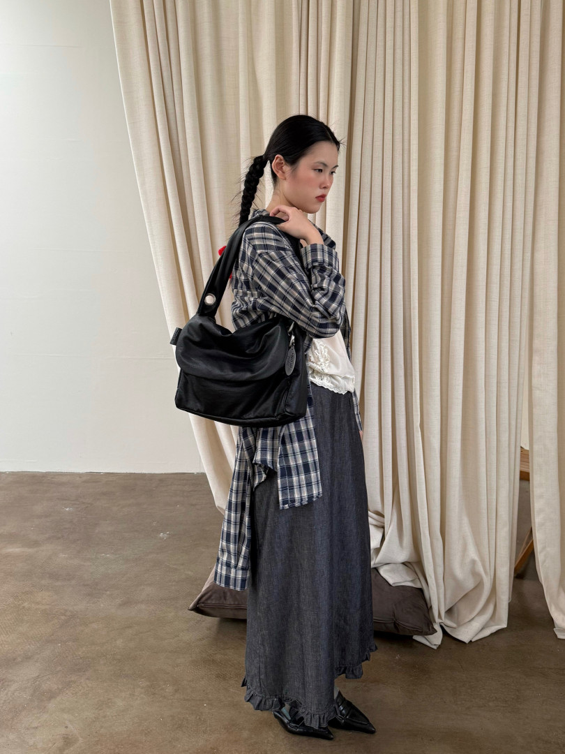 Model wearing a plaid layered outfit with a black shoulder bag
