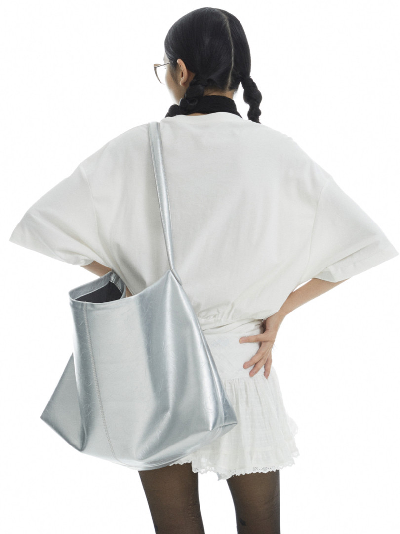 Model wearing a silver tote bag with a white outfit
