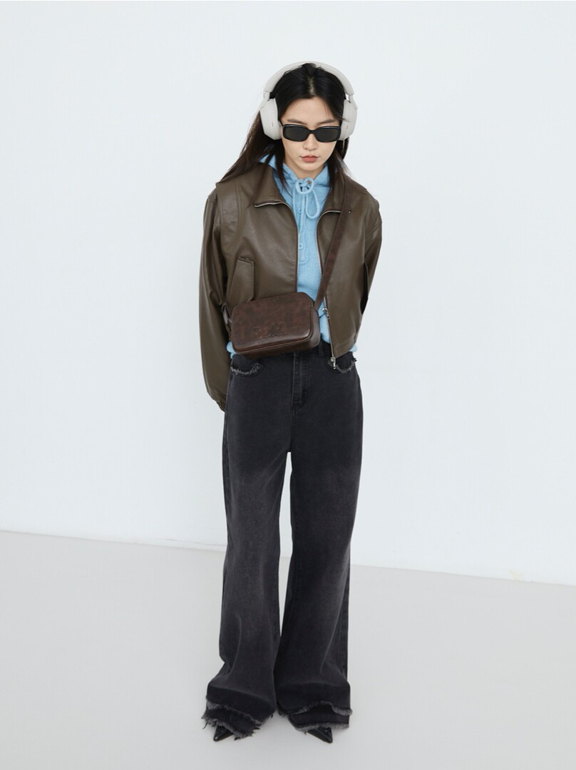 Model wearing a brown jacket with blue top, black wide-leg pants, and a crossbody bag