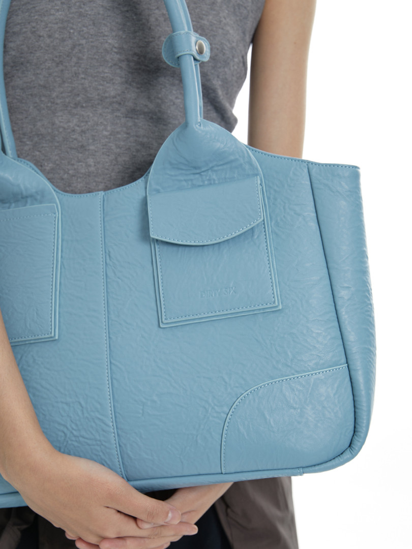 Light blue leather tote bag being held by a person