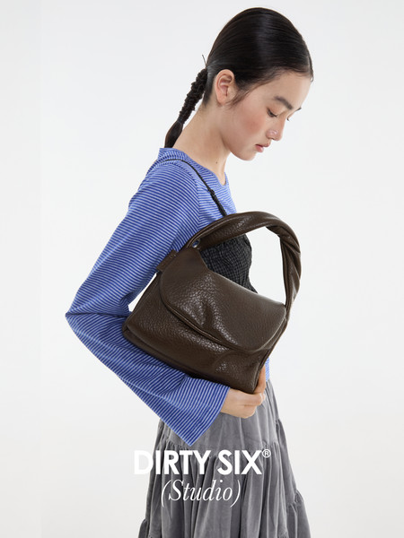Brown leather handbag worn by a model in a studio shot