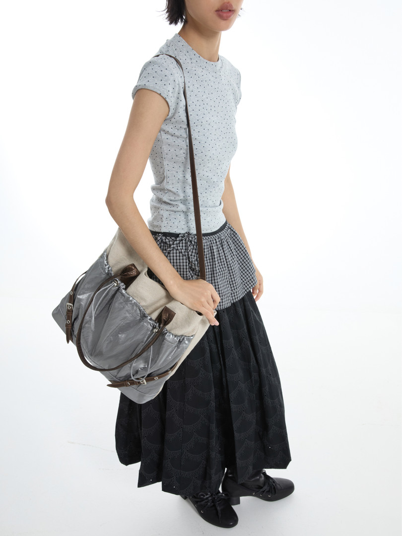 Model wearing a grey dotted top with a large shoulder bag and black skirt