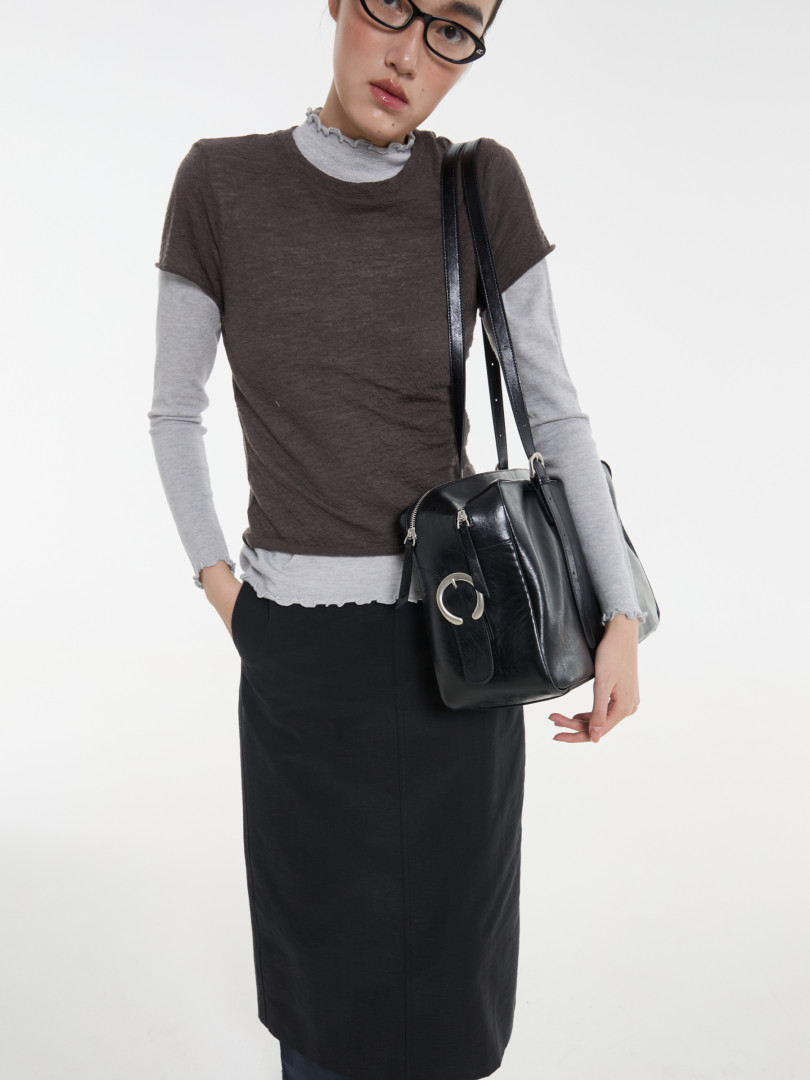 Model wearing layered casual outfit with a black shoulder bag